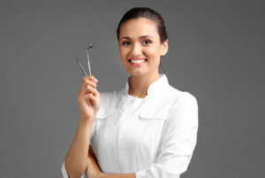 dentist smiling and holding tools